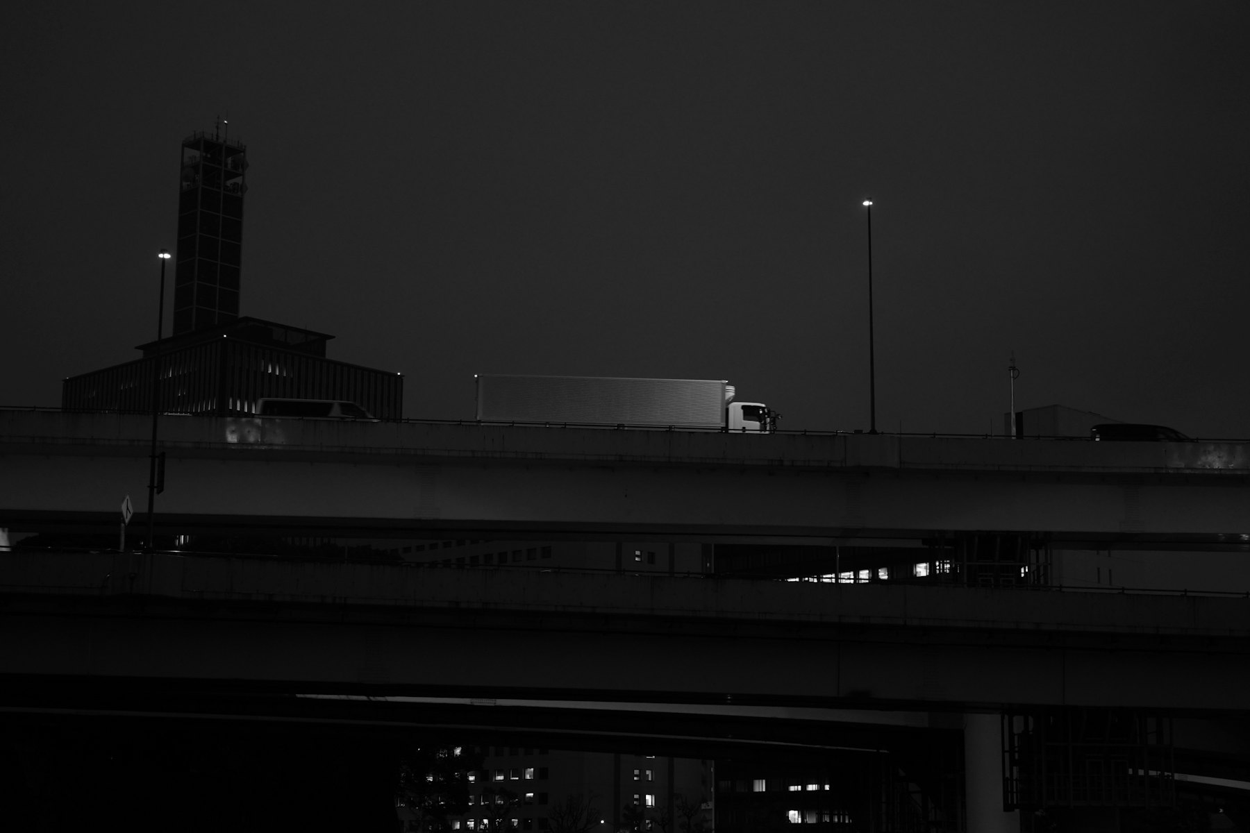 A trailer crossing an elevated span at night, seen from below.