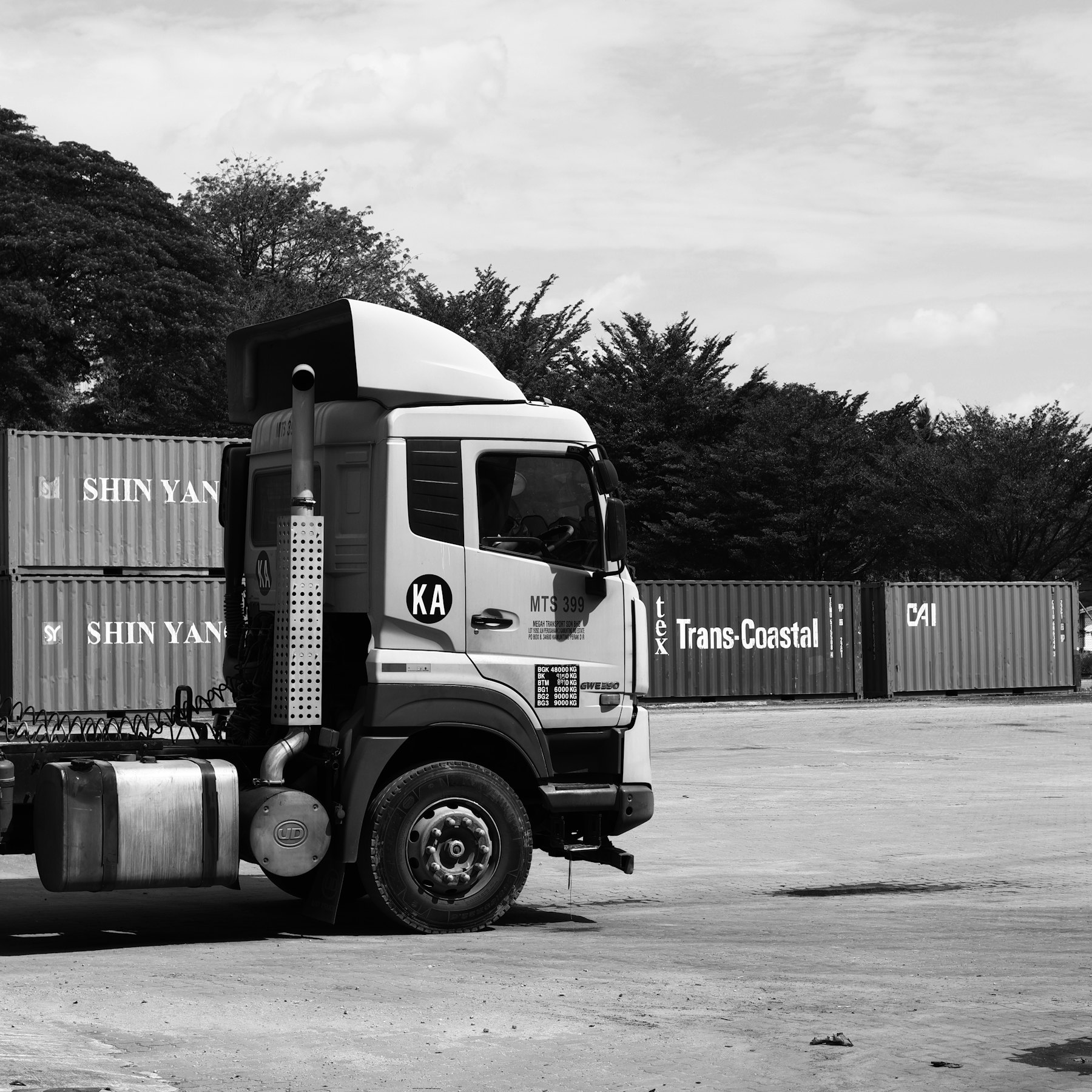A tractor parked among stacked containers in a yard.