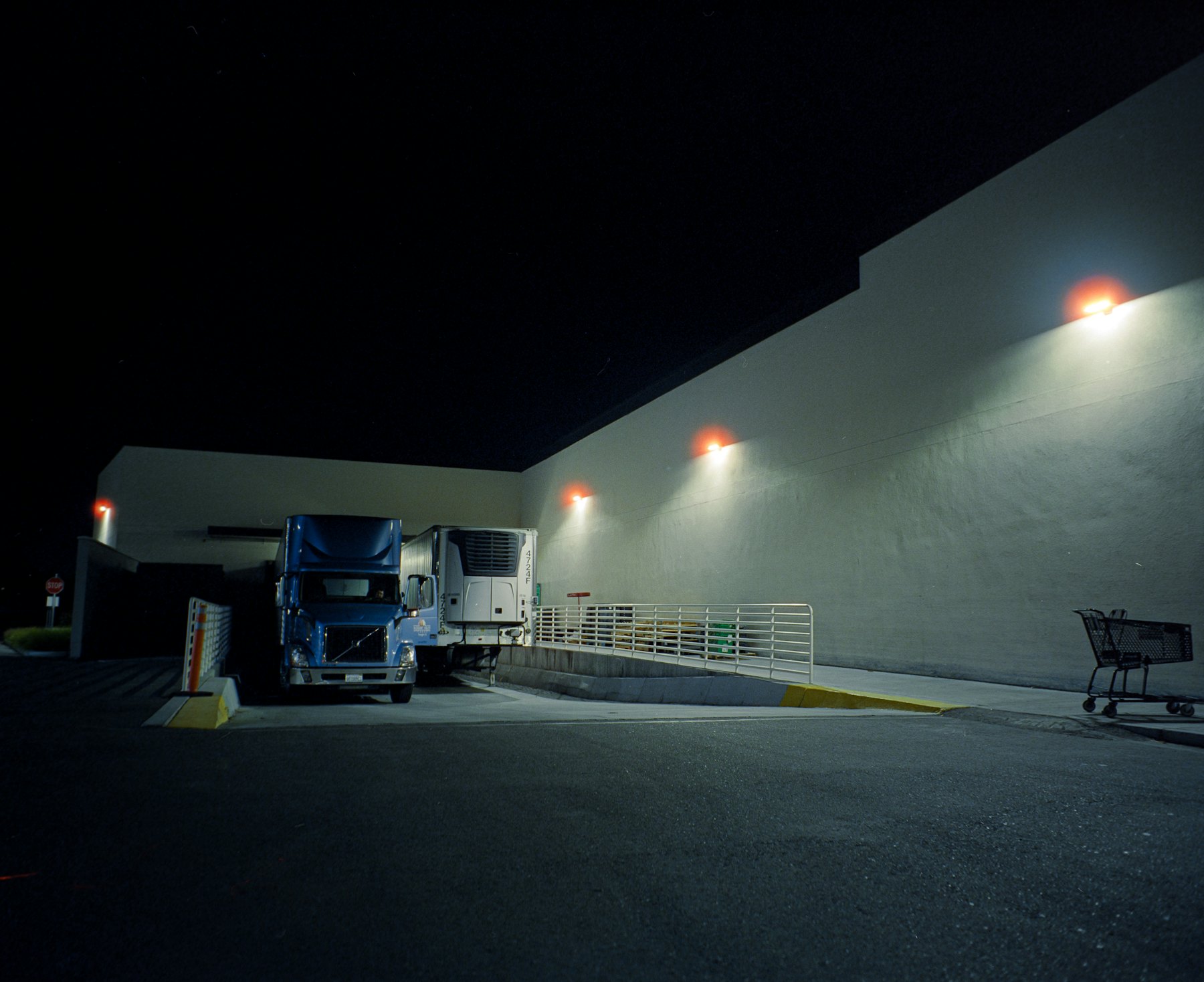 A reefer trailer backed into a dock at night under sodium lamps.